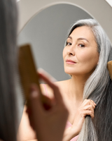 woman with graying hair brushing hair