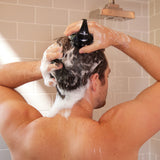 Man using Zenagen scalp massager in shower