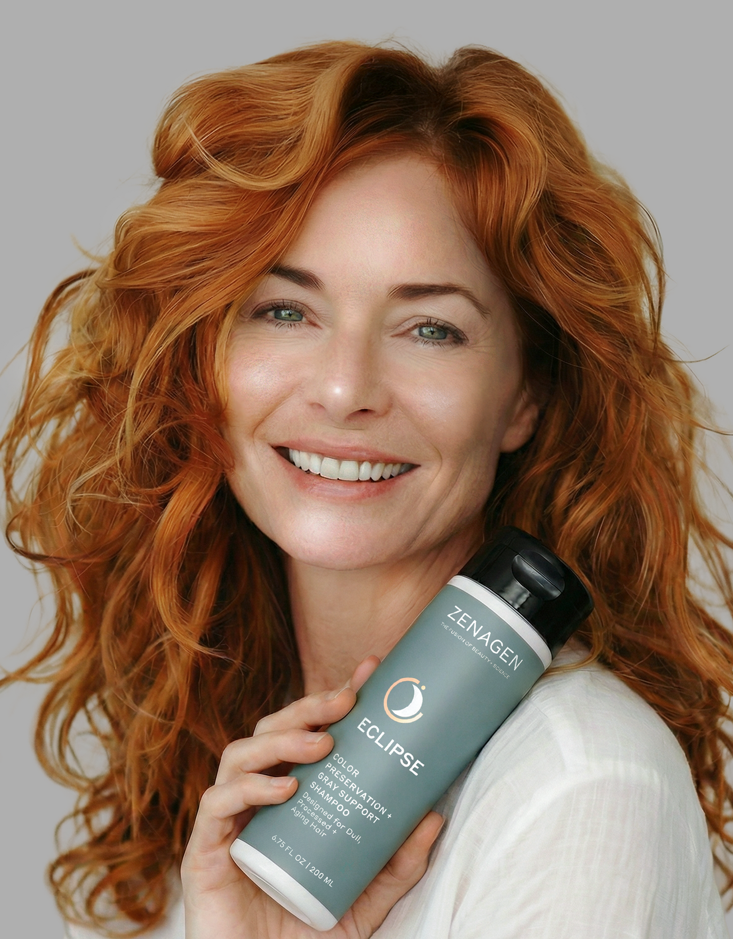 Woman with vibrant red hair holding Zenagen Eclipse shampoo designed to help maintain color vibrancy and enhance shine for color-treated hair