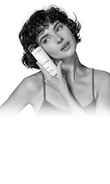 Woman holding Zenagen Revolve Women’s Shampoo for thinning hair, promoting volume, scalp health, and stronger-looking hair.