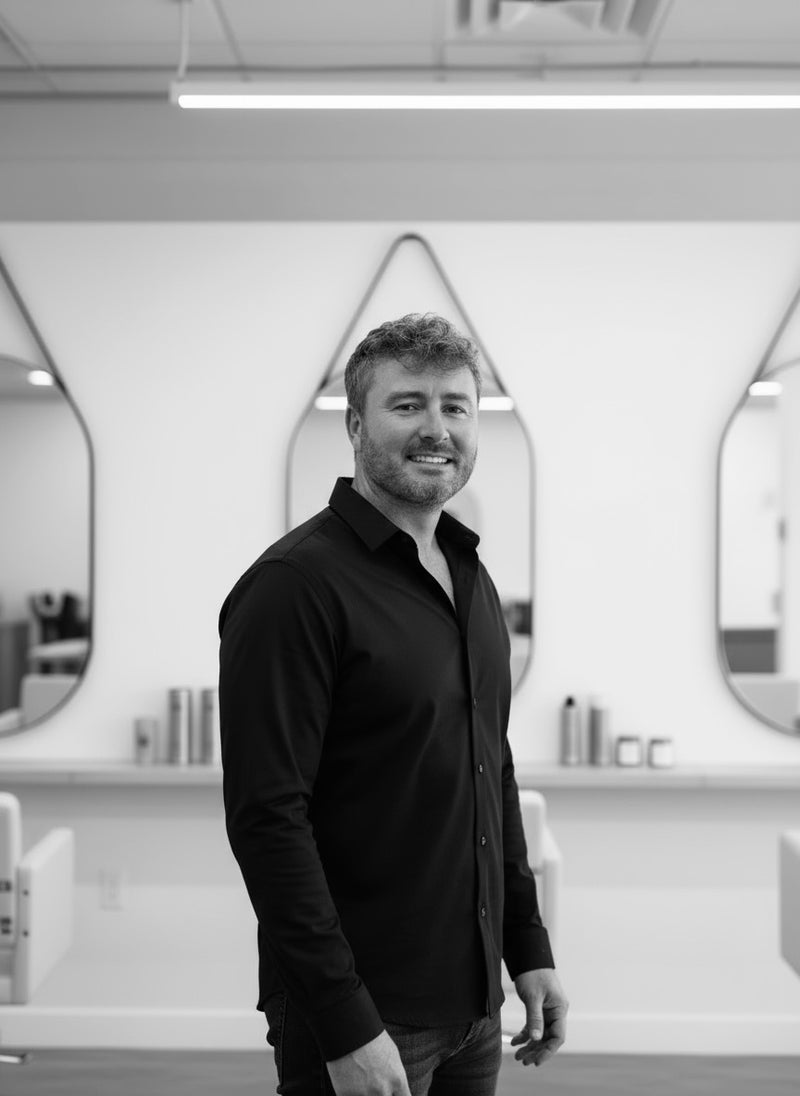 Zenagen founder Jared Reynolds standing in a modern salon with mirrors and chairs.